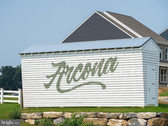 view of side of home with fence and metal roof