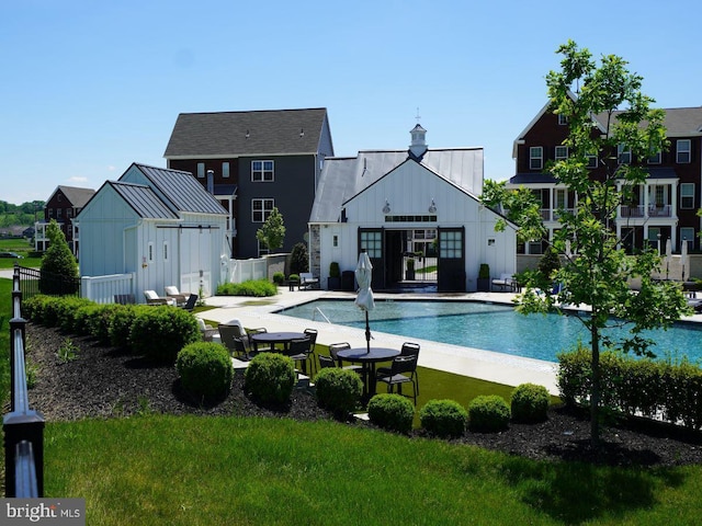 pool featuring a yard, an outbuilding, a patio area, and fence