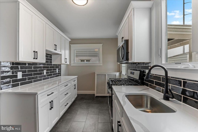 kitchen featuring backsplash, sink, white cabinetry, light stone countertops, and appliances with stainless steel finishes