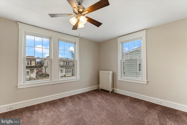 carpeted empty room with ceiling fan and radiator