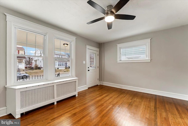 entryway with ceiling fan, wood-type flooring, a wealth of natural light, and radiator heating unit