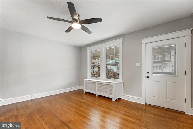 foyer entrance with ceiling fan, radiator, and hardwood / wood-style flooring