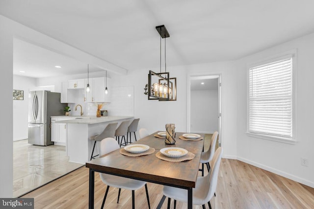 dining area with light wood-type flooring, a notable chandelier, and sink