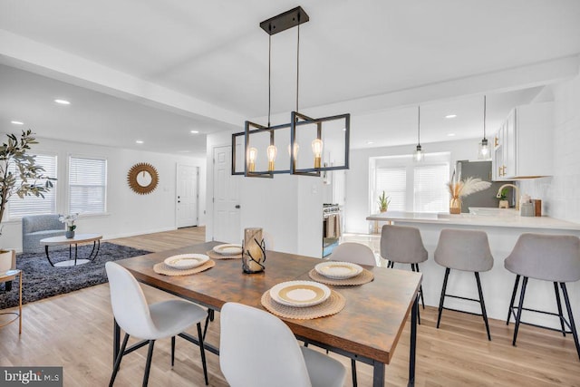 dining room featuring light hardwood / wood-style flooring, beam ceiling, and a healthy amount of sunlight