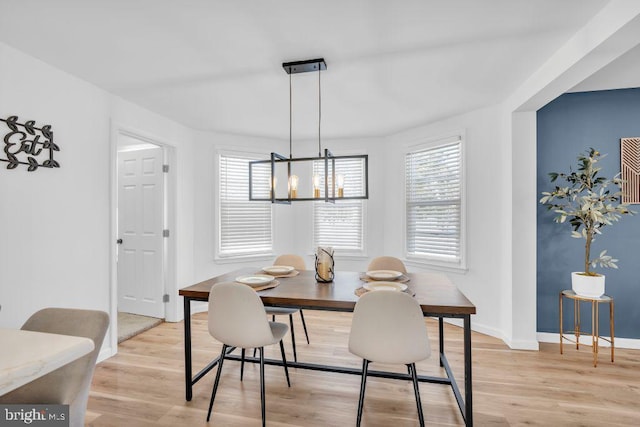 dining room with light wood-type flooring and a notable chandelier