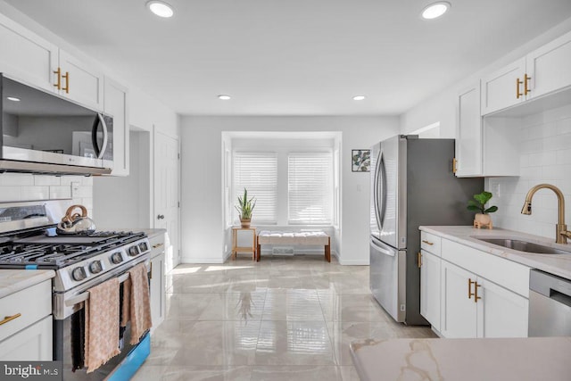 kitchen with sink, white cabinets, appliances with stainless steel finishes, and tasteful backsplash