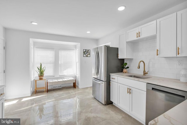 kitchen with decorative backsplash, sink, white cabinetry, light stone countertops, and appliances with stainless steel finishes