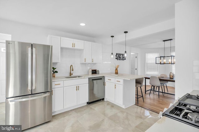 kitchen featuring pendant lighting, white cabinets, appliances with stainless steel finishes, sink, and kitchen peninsula