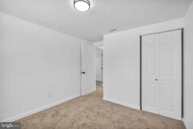 unfurnished bedroom with light carpet and a closet