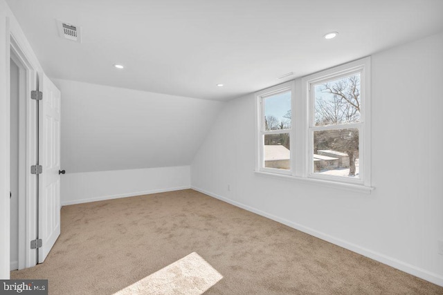 bonus room with light carpet and vaulted ceiling