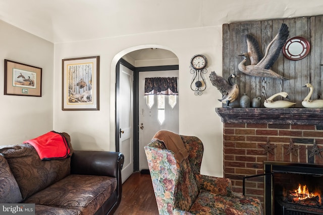 living room featuring a brick fireplace and dark hardwood / wood-style flooring