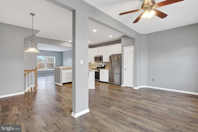 kitchen with stainless steel appliances, white cabinetry, dark wood-type flooring, and pendant lighting