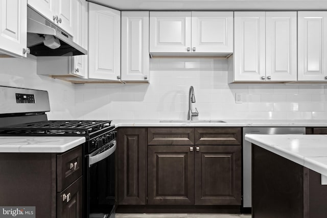 kitchen featuring appliances with stainless steel finishes, dark brown cabinetry, white cabinetry, sink, and backsplash