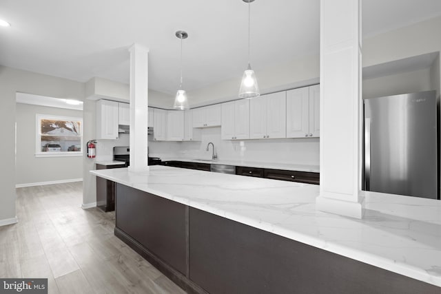 kitchen featuring pendant lighting, white cabinets, stainless steel appliances, sink, and light stone counters