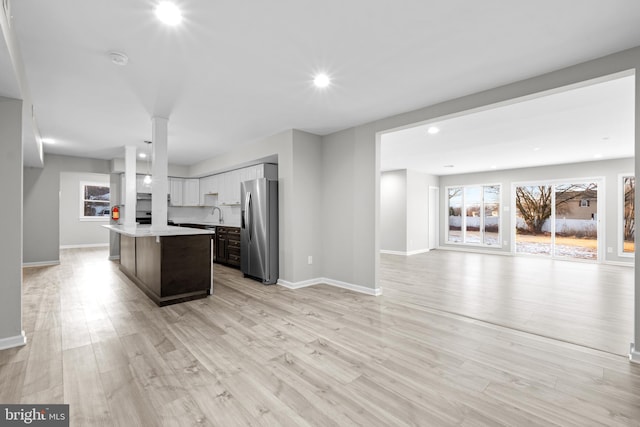 kitchen with dark brown cabinetry, light hardwood / wood-style flooring, stainless steel fridge, and a kitchen island