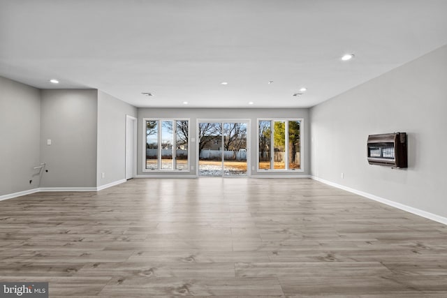 unfurnished living room featuring heating unit and light hardwood / wood-style flooring