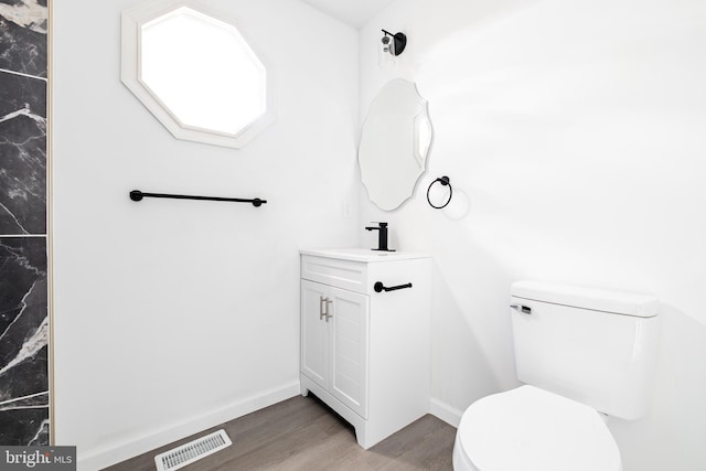 bathroom with toilet, vanity, and hardwood / wood-style flooring