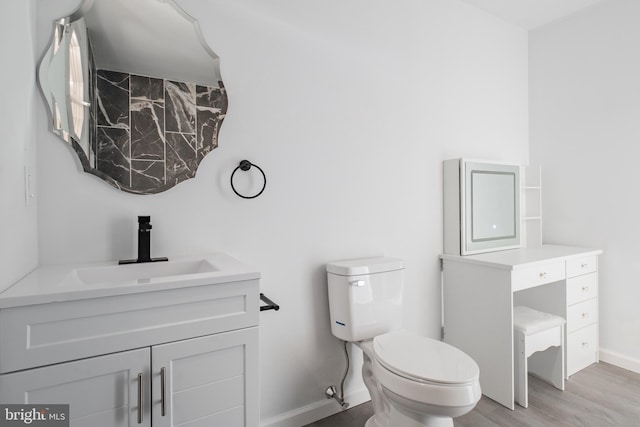 bathroom with wood-type flooring, toilet, and vanity