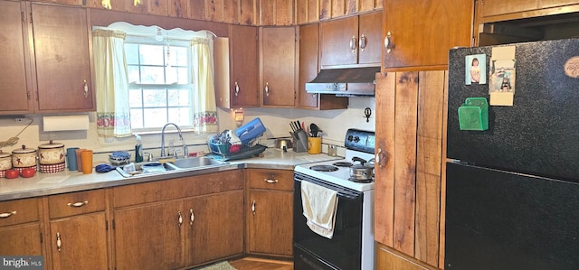 kitchen with under cabinet range hood, electric range oven, a sink, light countertops, and freestanding refrigerator