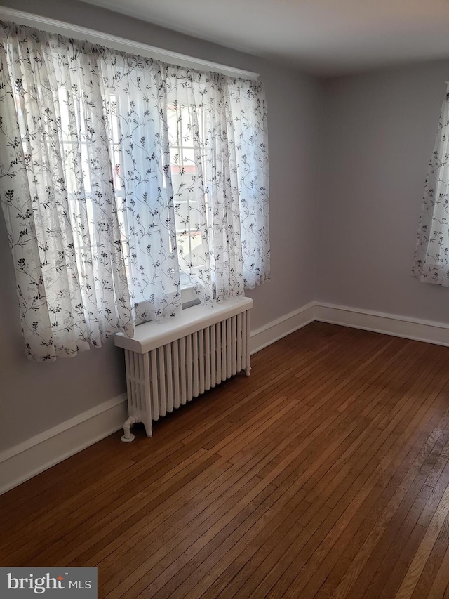 unfurnished room featuring radiator and wood-type flooring