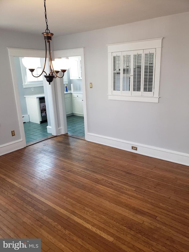 unfurnished dining area featuring baseboard heating, dark hardwood / wood-style flooring, and an inviting chandelier