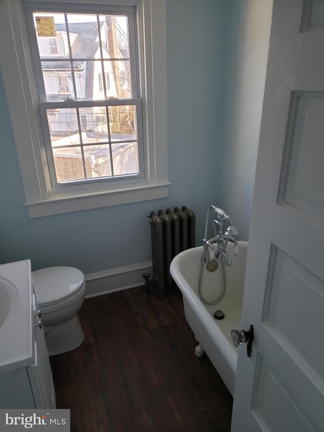 bathroom with hardwood / wood-style floors, radiator, vanity, toilet, and a bathing tub