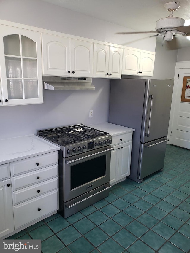 kitchen with high end appliances, ceiling fan, white cabinetry, and tile patterned floors