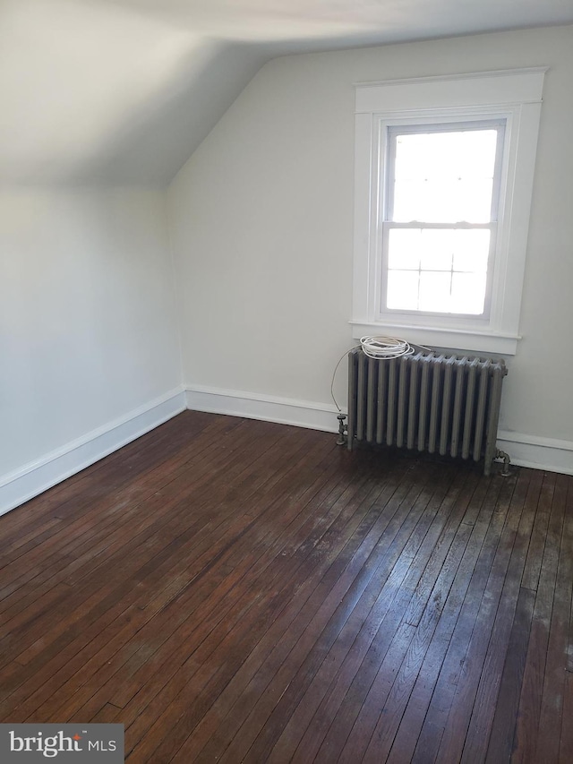 additional living space with radiator, lofted ceiling, and dark hardwood / wood-style floors