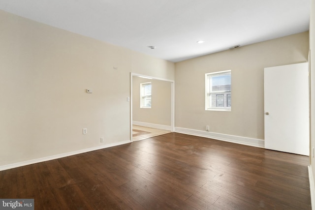 empty room with plenty of natural light and dark hardwood / wood-style floors