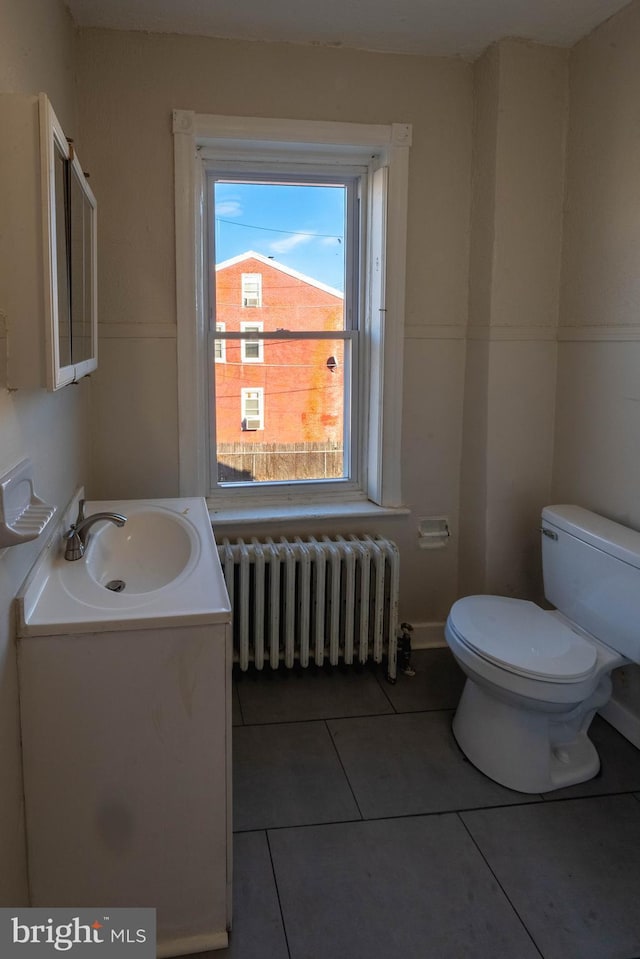 bathroom with toilet, radiator, vanity, and tile patterned flooring