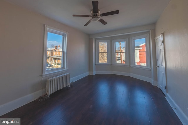 unfurnished room with radiator, ceiling fan, and dark wood-type flooring