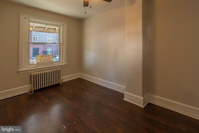 empty room featuring ceiling fan, dark hardwood / wood-style floors, and radiator heating unit