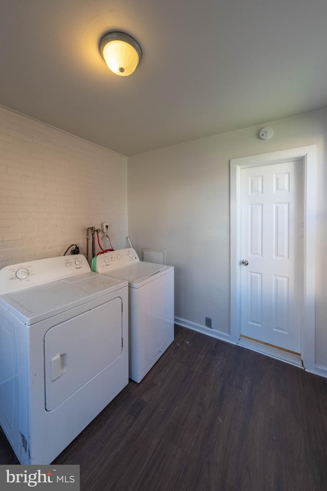 washroom featuring brick wall, dark hardwood / wood-style floors, and washing machine and clothes dryer