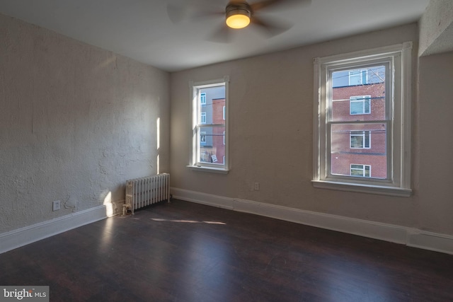 unfurnished room featuring ceiling fan, dark hardwood / wood-style floors, and radiator heating unit