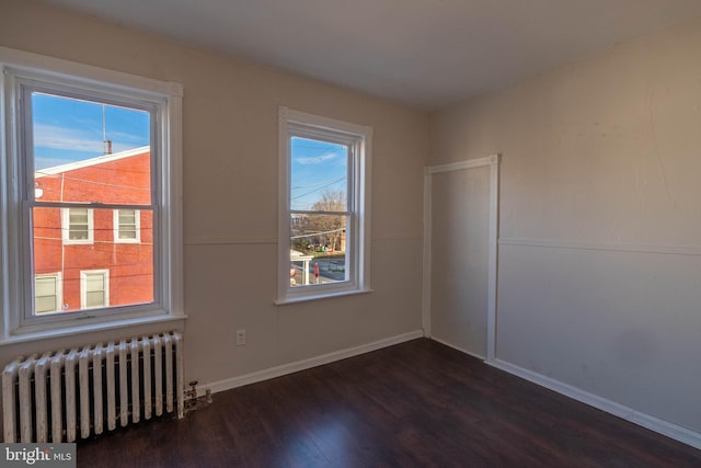 spare room with radiator, dark wood-type flooring, and a wealth of natural light