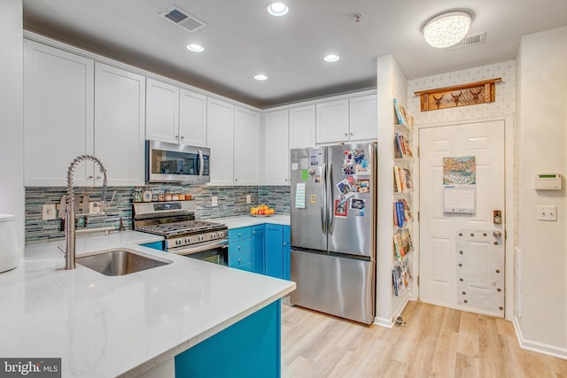 kitchen featuring sink, stainless steel appliances, white cabinets, and blue cabinetry