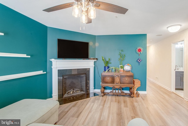 living room with ceiling fan, a tile fireplace, and light hardwood / wood-style flooring