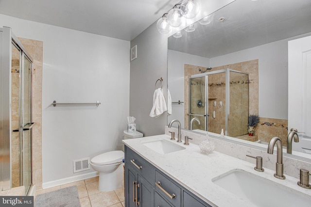 bathroom featuring tile patterned flooring, vanity, a shower with shower door, and toilet