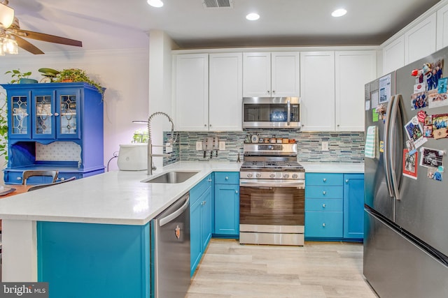 kitchen featuring appliances with stainless steel finishes, sink, white cabinets, and blue cabinetry