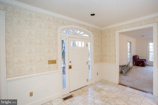 carpeted foyer featuring ornamental molding