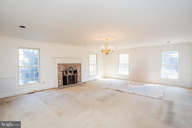 unfurnished living room with light carpet, a fireplace, crown molding, and an inviting chandelier