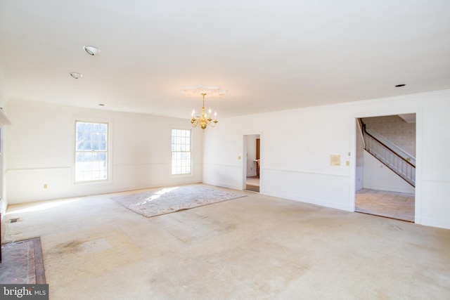 empty room featuring carpet, crown molding, and a chandelier