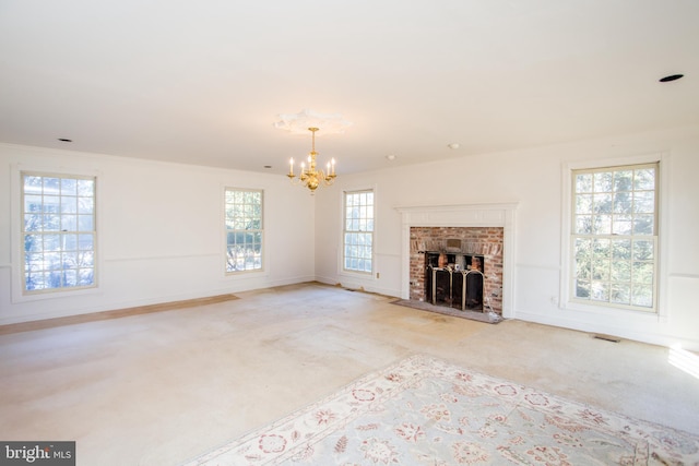 unfurnished living room with light colored carpet, a fireplace, a wealth of natural light, and an inviting chandelier