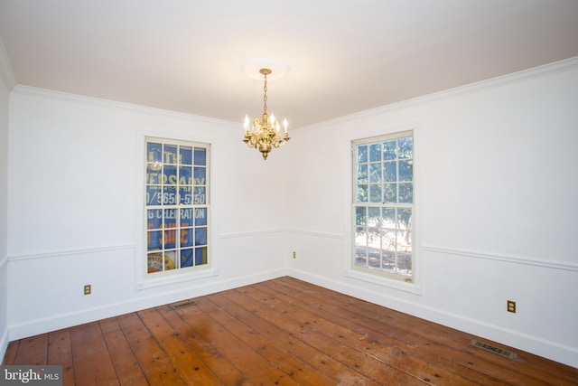 spare room featuring wood-type flooring, crown molding, and a chandelier