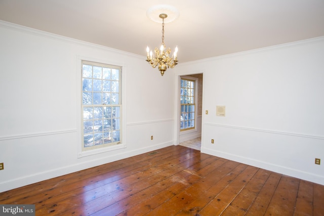 empty room featuring dark hardwood / wood-style floors, crown molding, and a chandelier