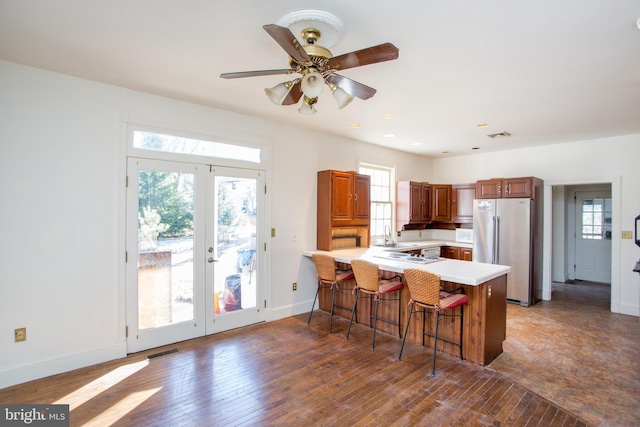 kitchen with a kitchen bar, kitchen peninsula, high quality fridge, french doors, and sink