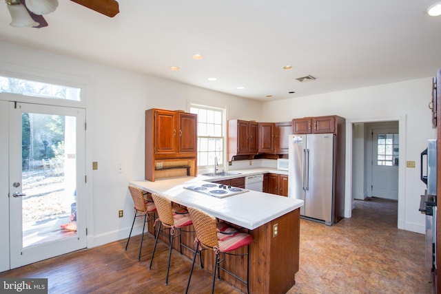 kitchen with ceiling fan, kitchen peninsula, sink, white appliances, and a breakfast bar area