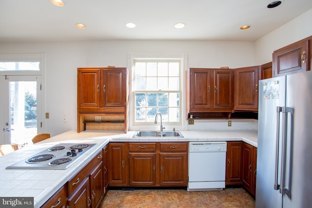 kitchen with tile countertops, a wealth of natural light, sink, and white appliances