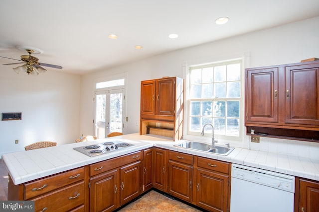 kitchen with tile counters, kitchen peninsula, sink, and white appliances