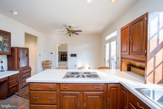 kitchen with tile countertops, kitchen peninsula, ceiling fan, french doors, and white stovetop